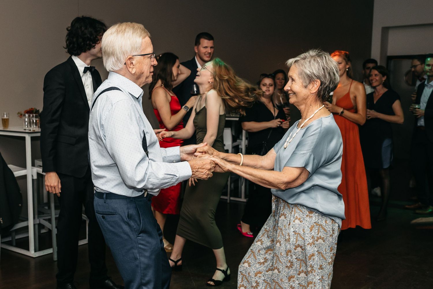 Elderly couple dancing together joyfully at a lively wedding reception.