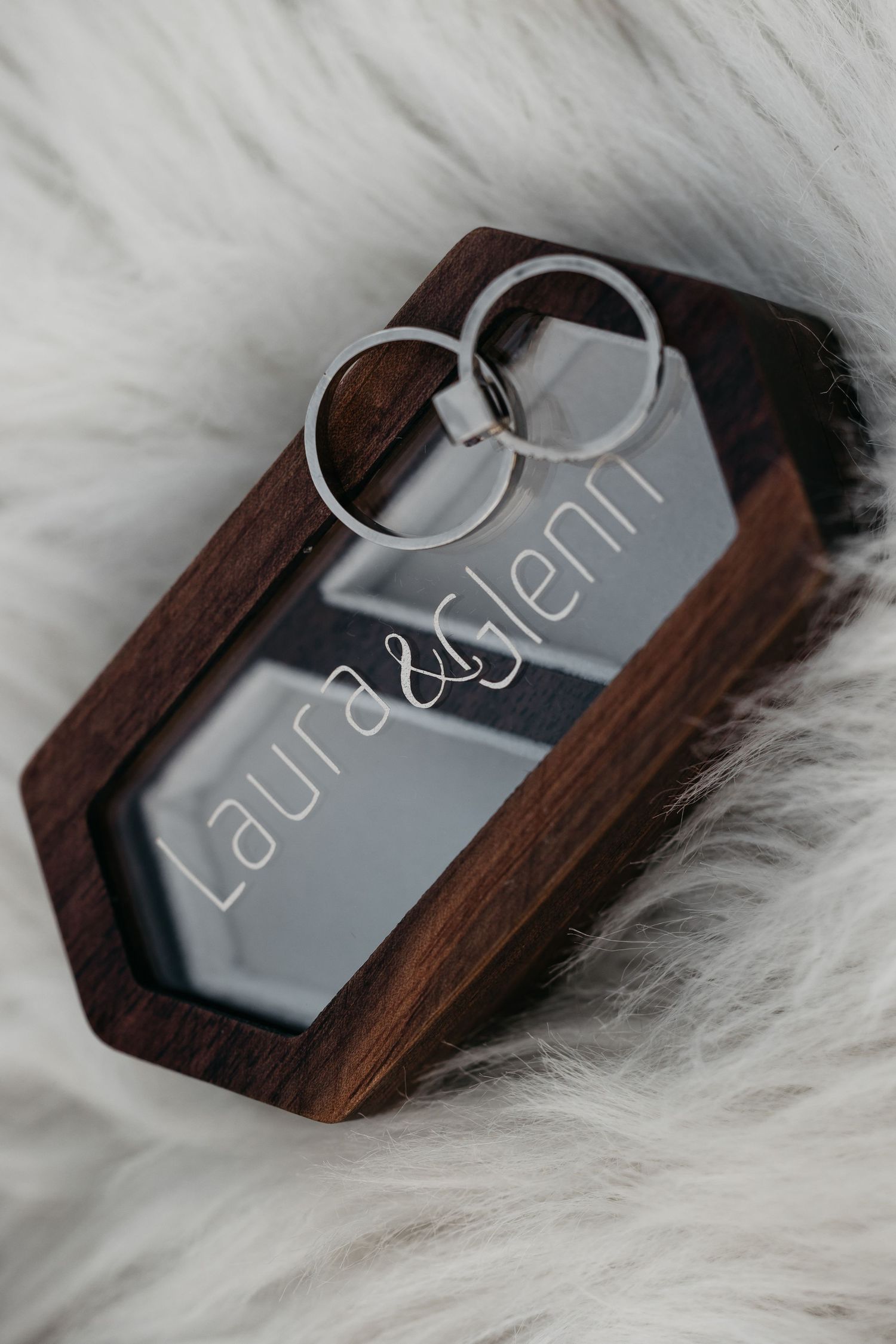 Wedding rings resting in a hexagonal wooden ring box engraved with Laura and Glenn.