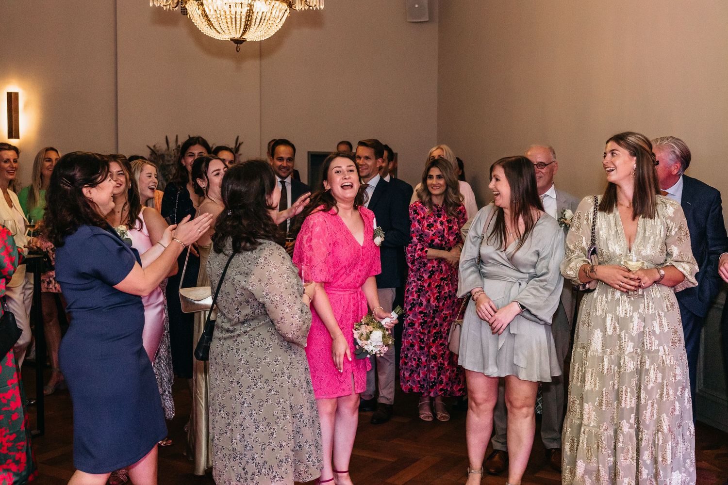 Guests laughing and celebrating at a wedding reception in an elegant ballroom.