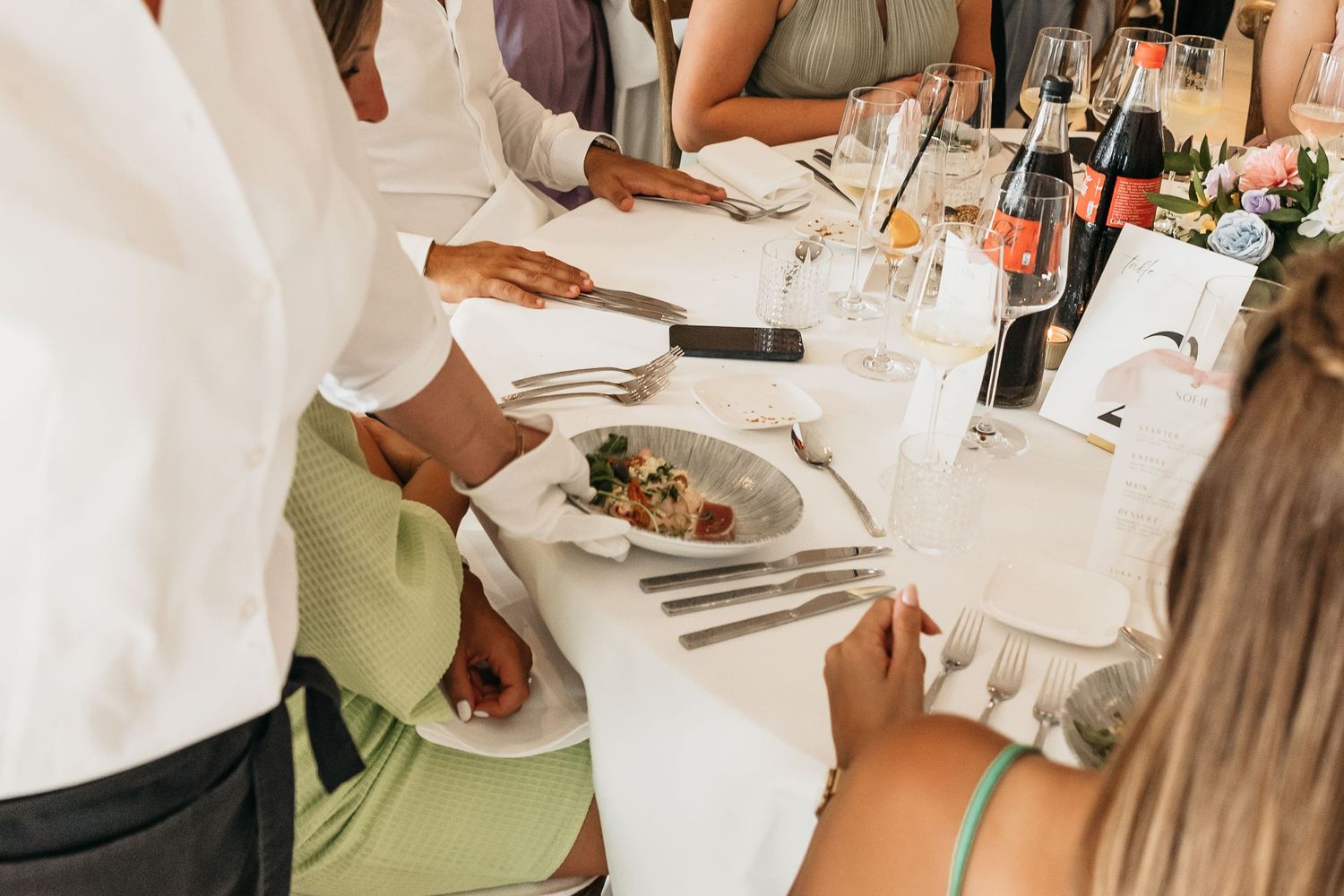 Server presenting a plated meal to a guest at a formal wedding reception dinner.