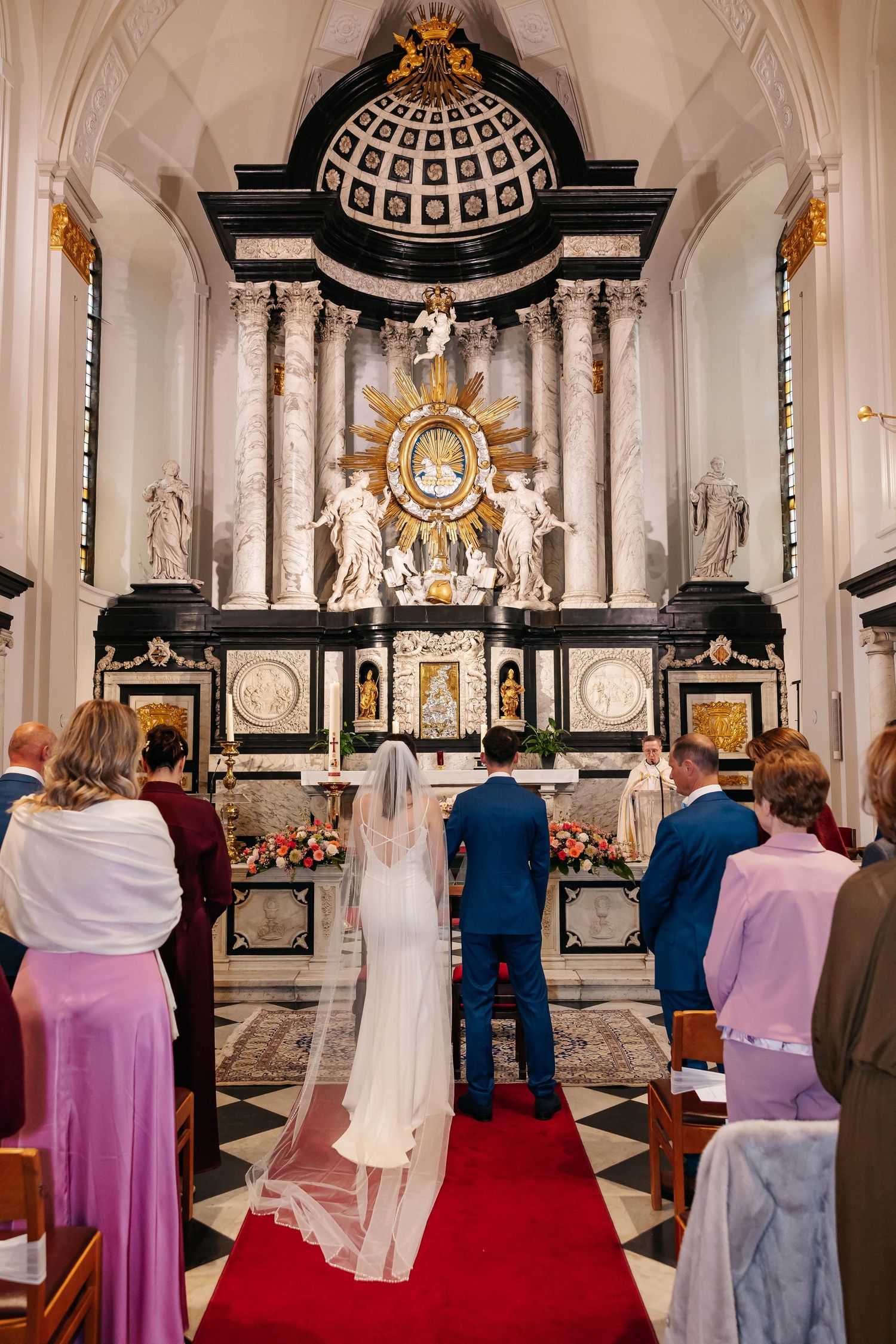 Bride and groom standing before ornate baroque altar during wedding ceremony in a historic church.
