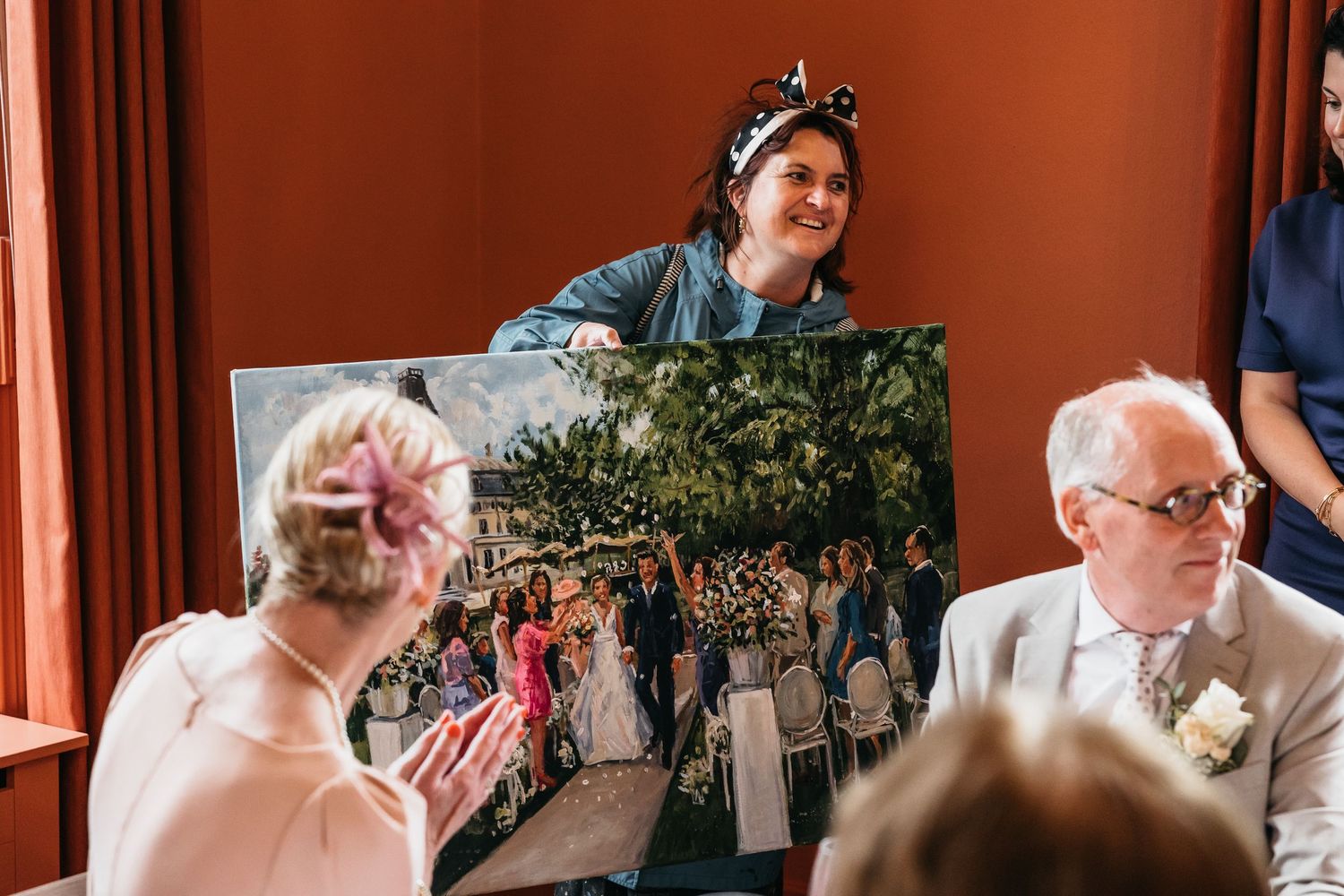 Wedding guest holds large canvas photo print at reception dinner table.