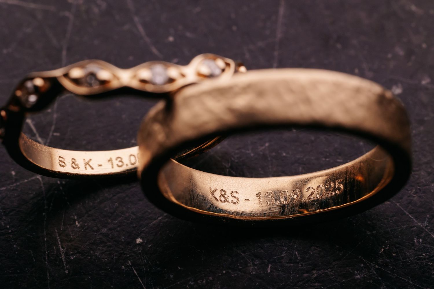 Two engraved gold wedding bands with personalized inscriptions S&K and K&S with wedding date 2025.