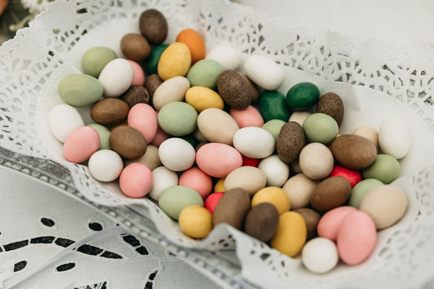 Colorful chocolate-coated candies arranged in a white lace-lined dish at a wedding reception.