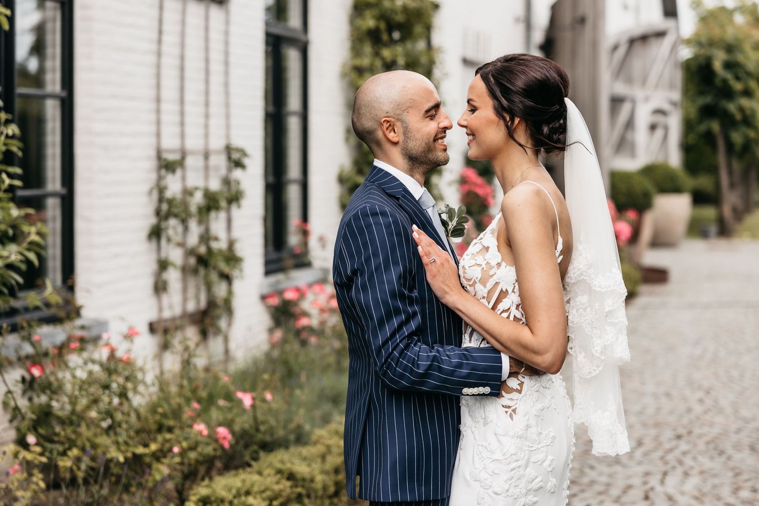 Bride and groom share an intimate moment facing each other in a charming garden setting.