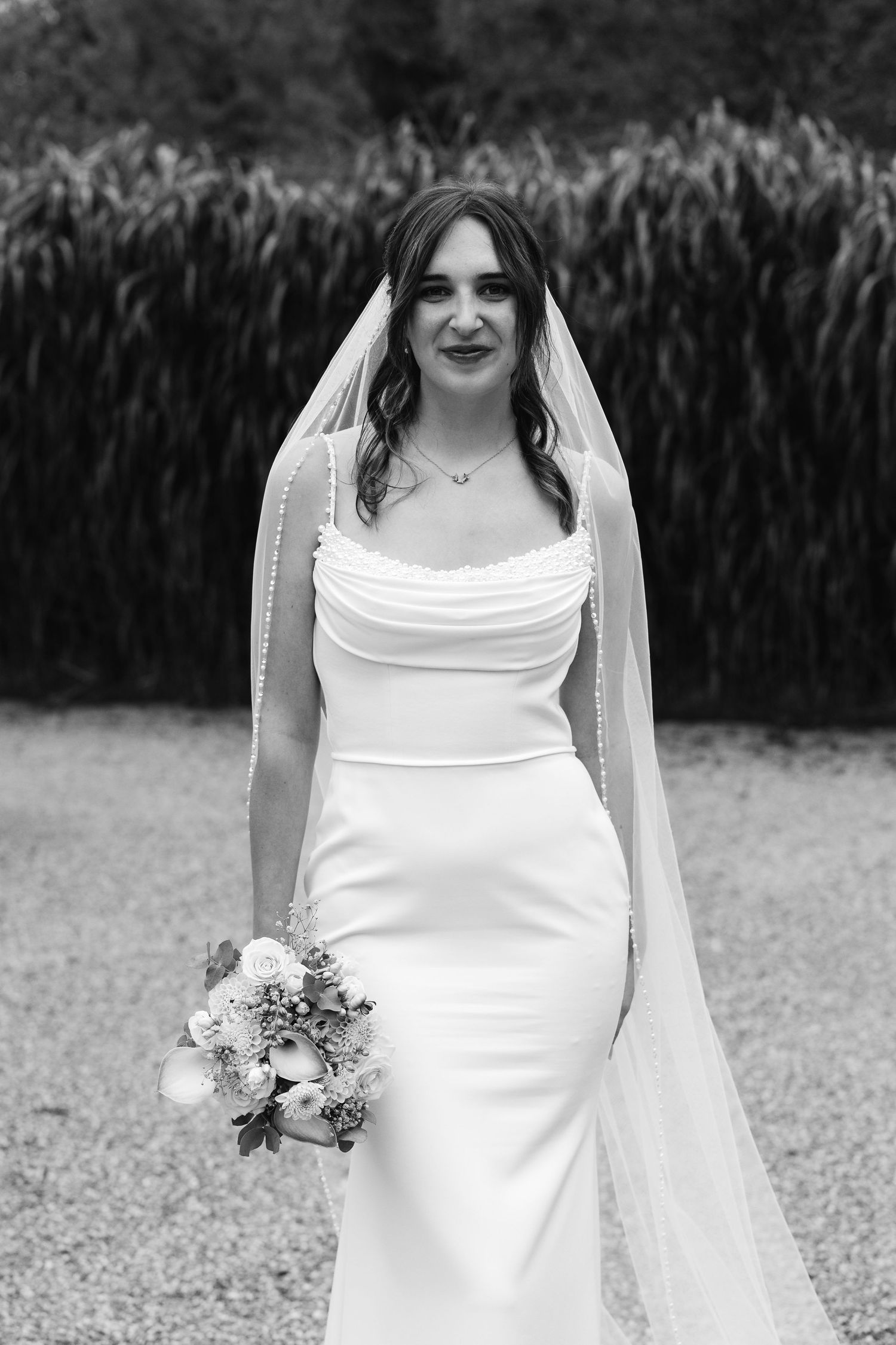 Classic black and white bridal portrait featuring fitted white dress, long veil, and bouquet.