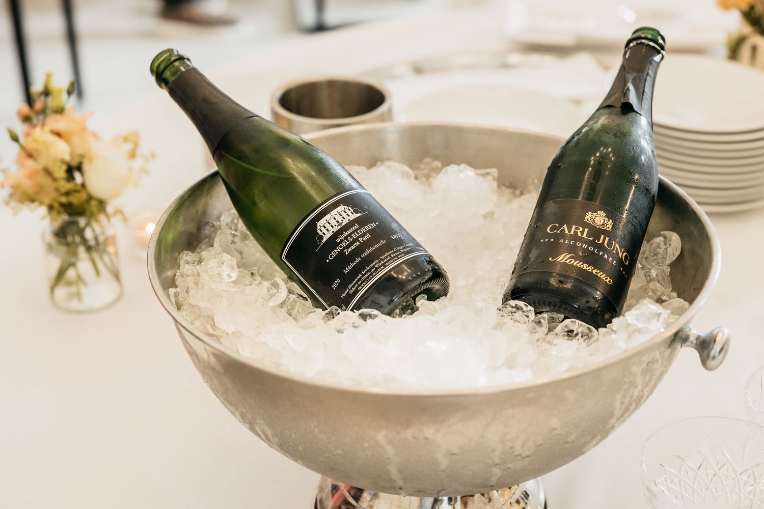 Two champagne bottles chilling in a silver ice bucket at a wedding reception.