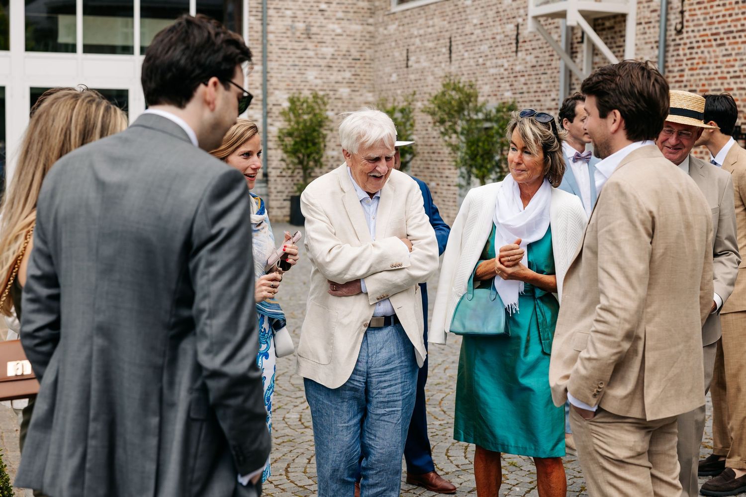Elegantly dressed wedding guests socializing outdoors at a summer reception.