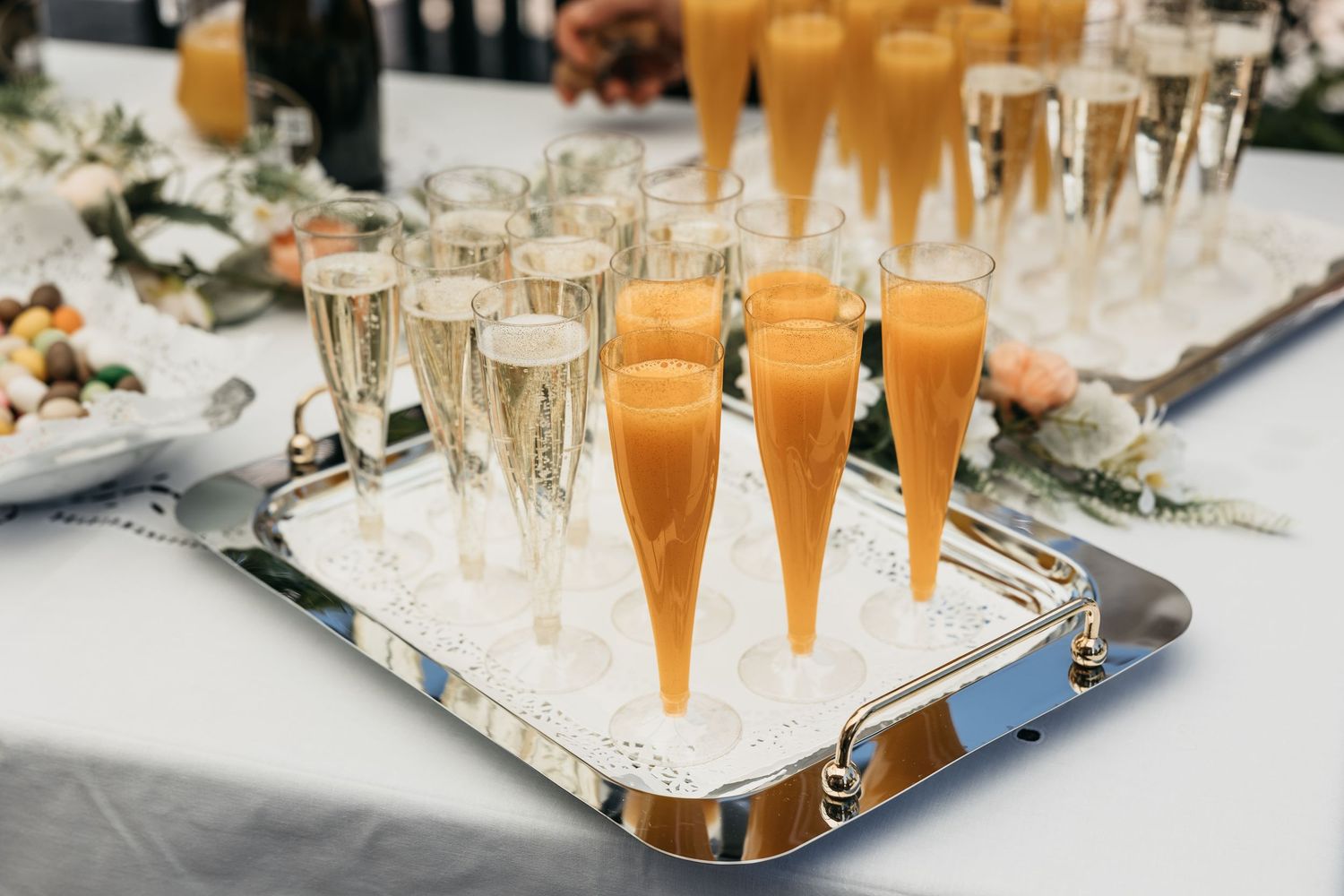 Elegant silver tray with champagne flutes and orange juice glasses at a wedding reception.