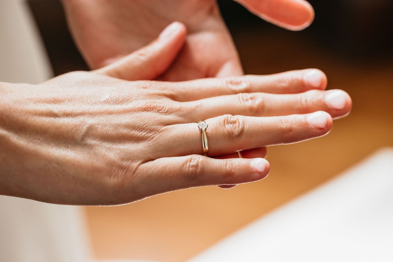 Close-up of a delicate gold wedding band on a bride's finger after ceremony.