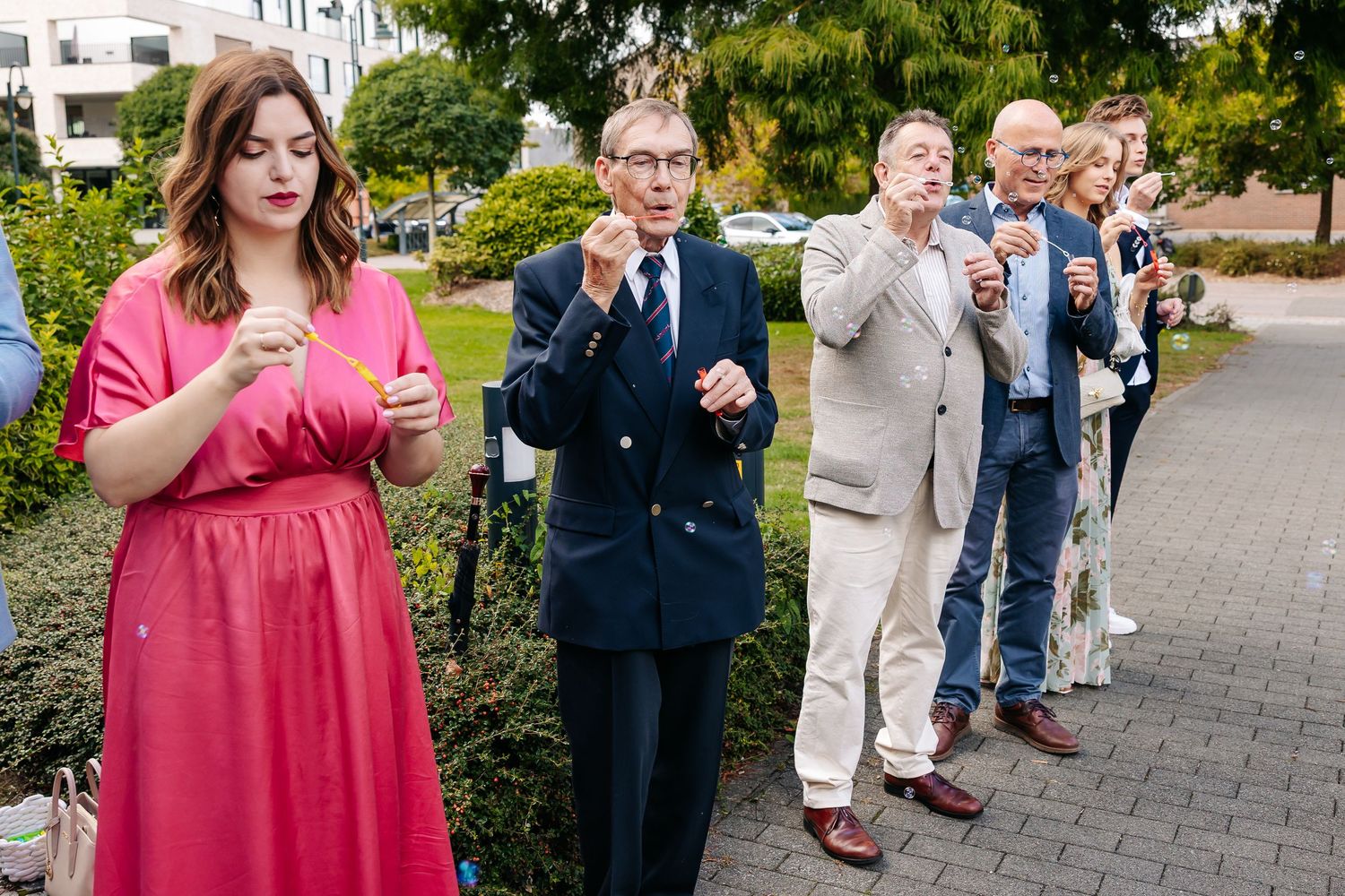 Wedding guests blowing bubbles outdoors to celebrate bride and groom at their wedding.