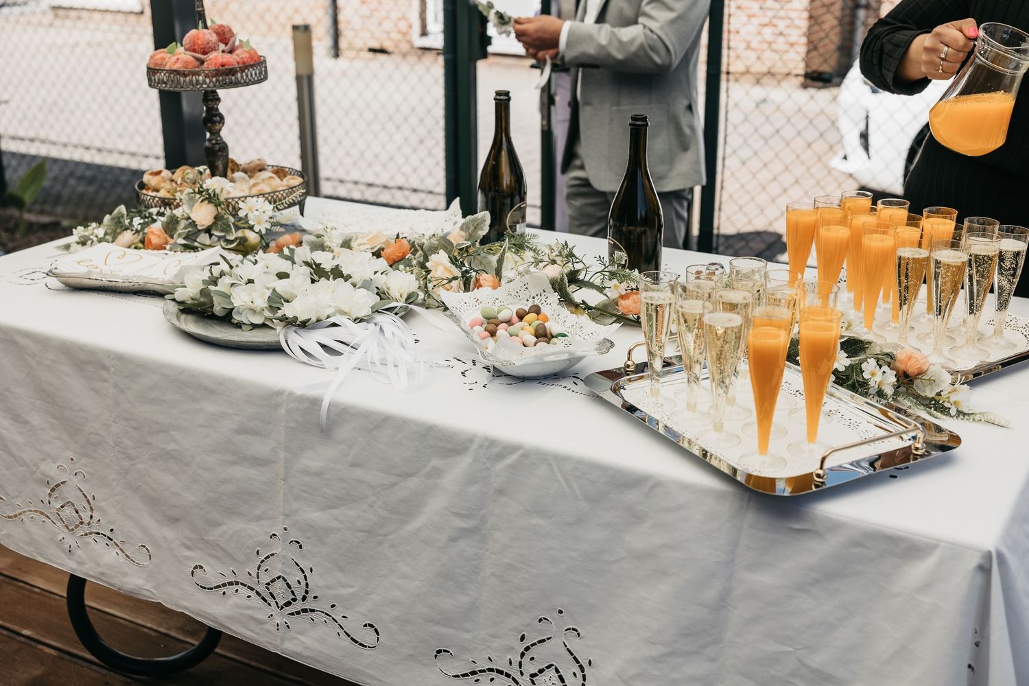 Wedding reception buffet table with champagne flutes, orange juice, and elegant floral decor.