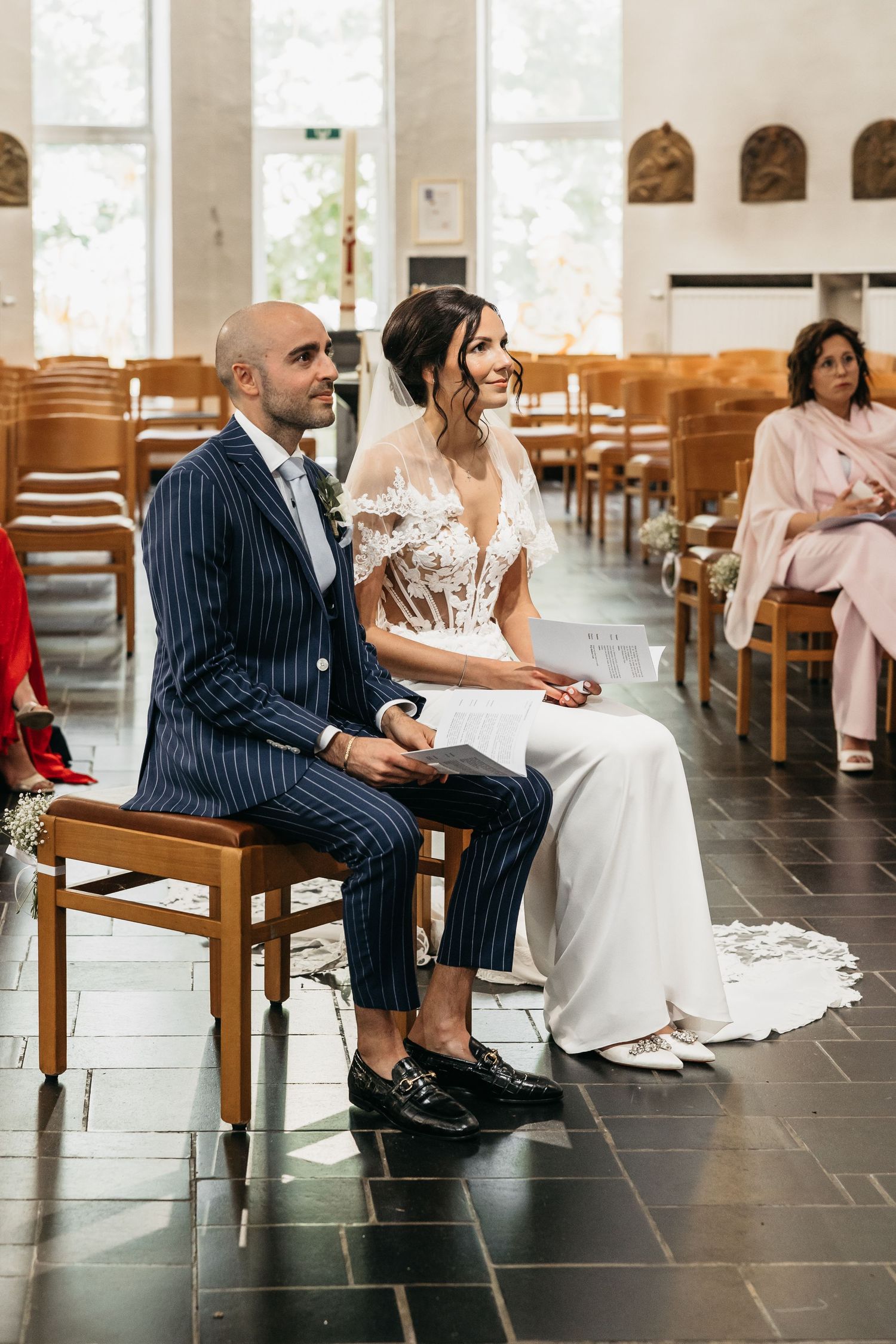 Bride and groom sit together smiling during church wedding ceremony.