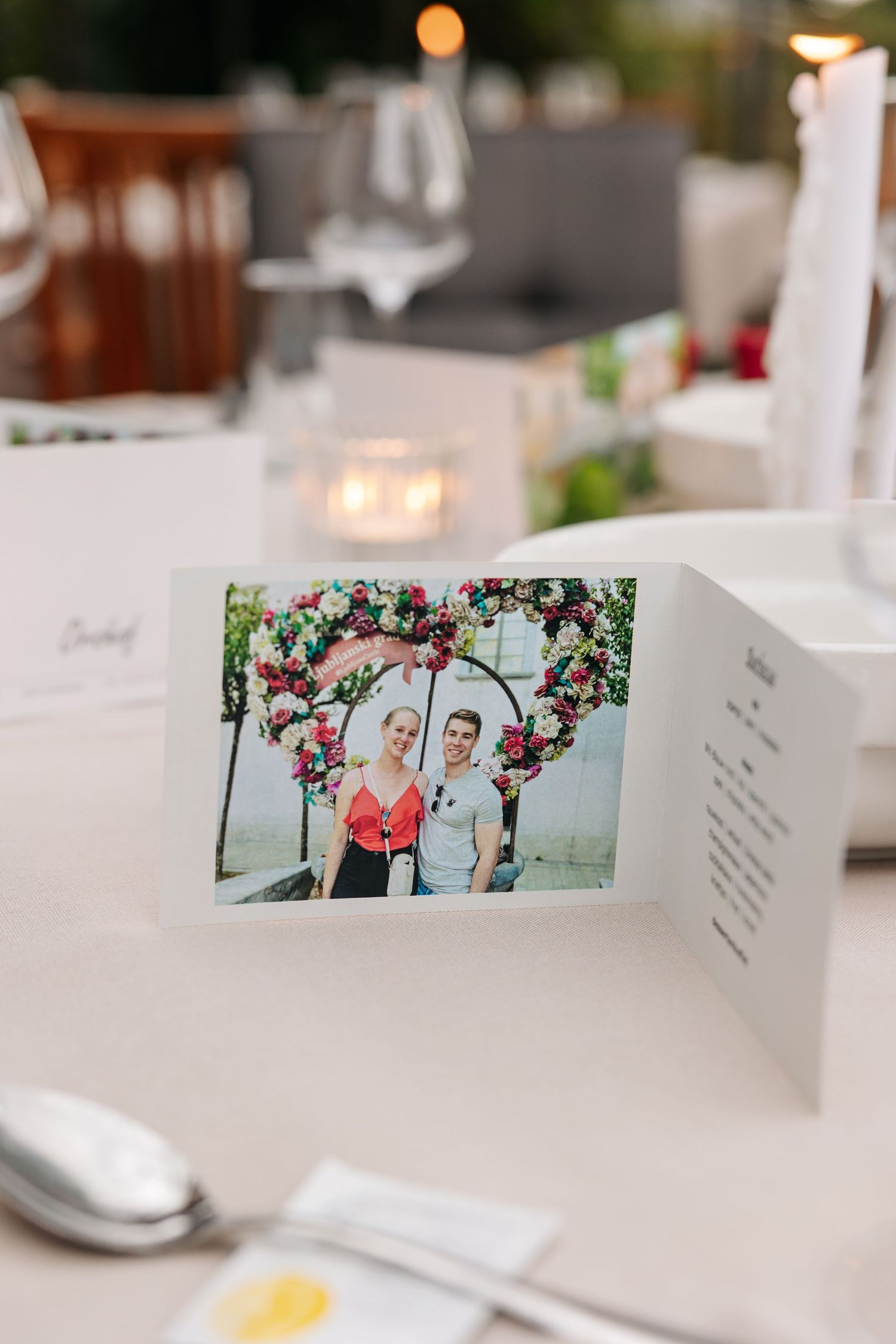 A wedding place card featuring a couple photo displayed on an elegantly set reception table.