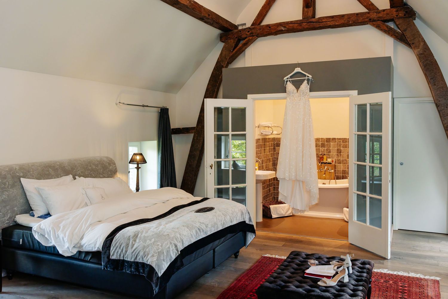 Elegant bridal suite with exposed beams, wedding dress hanging on door.