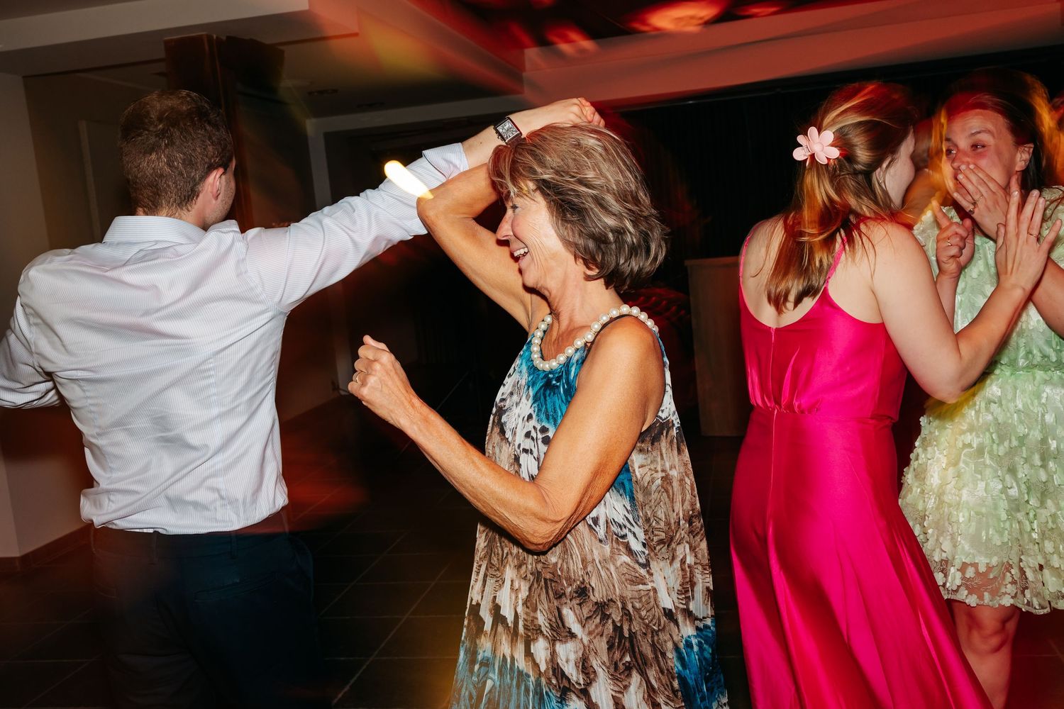 Guests dancing energetically on the wedding reception dance floor at night.
