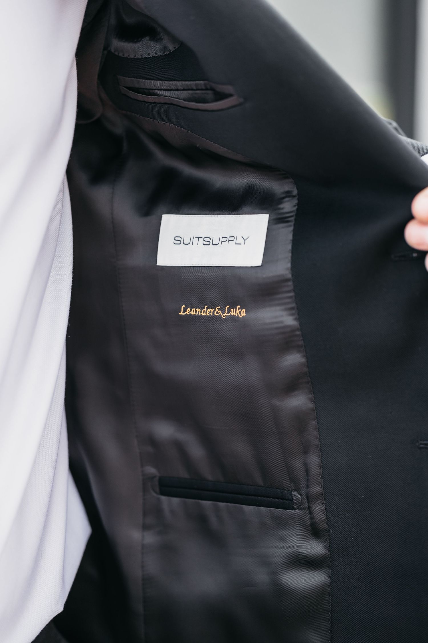 Interior label of Suitsupply wedding suit jacket with personalized gold embroidered name tag.