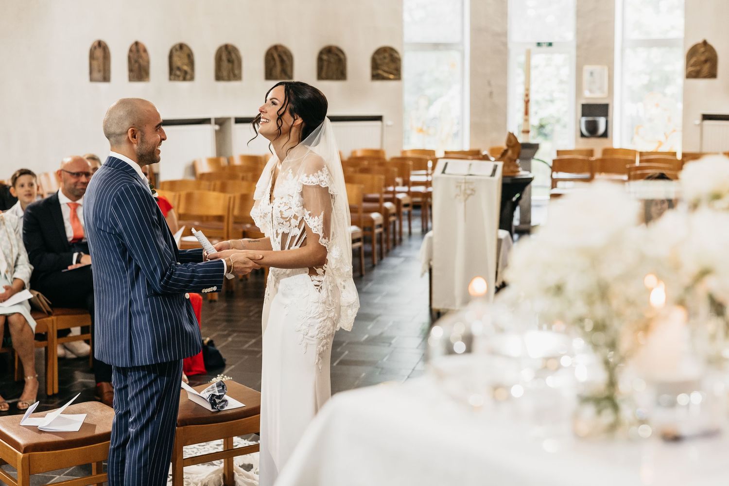 Bride and groom stand at church altar during wedding ceremony with floral decorations.