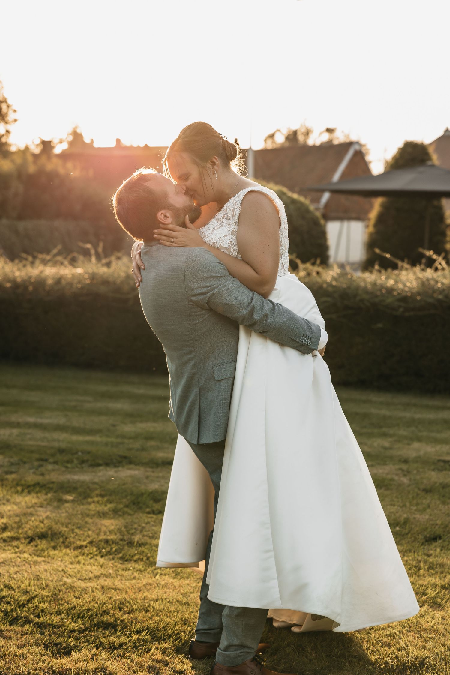 Bride and groom sharing romantic kiss outdoors in beautiful golden sunset light.