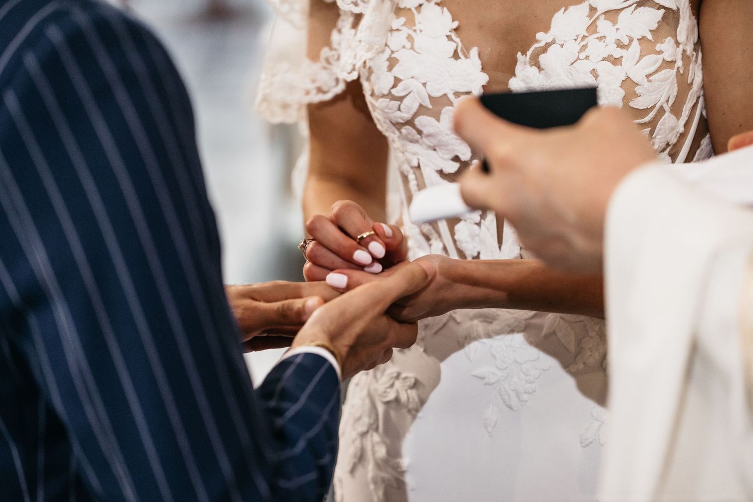 Close-up of officiant guiding couple during wedding ring exchange ceremony.