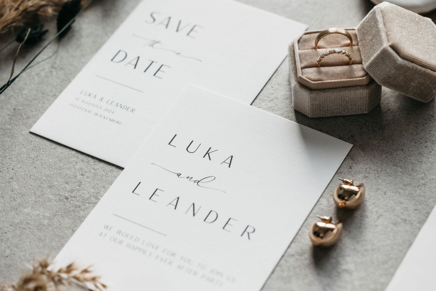 Minimalist wedding stationery flat lay with save the date cards, gold rings and delicate earrings.