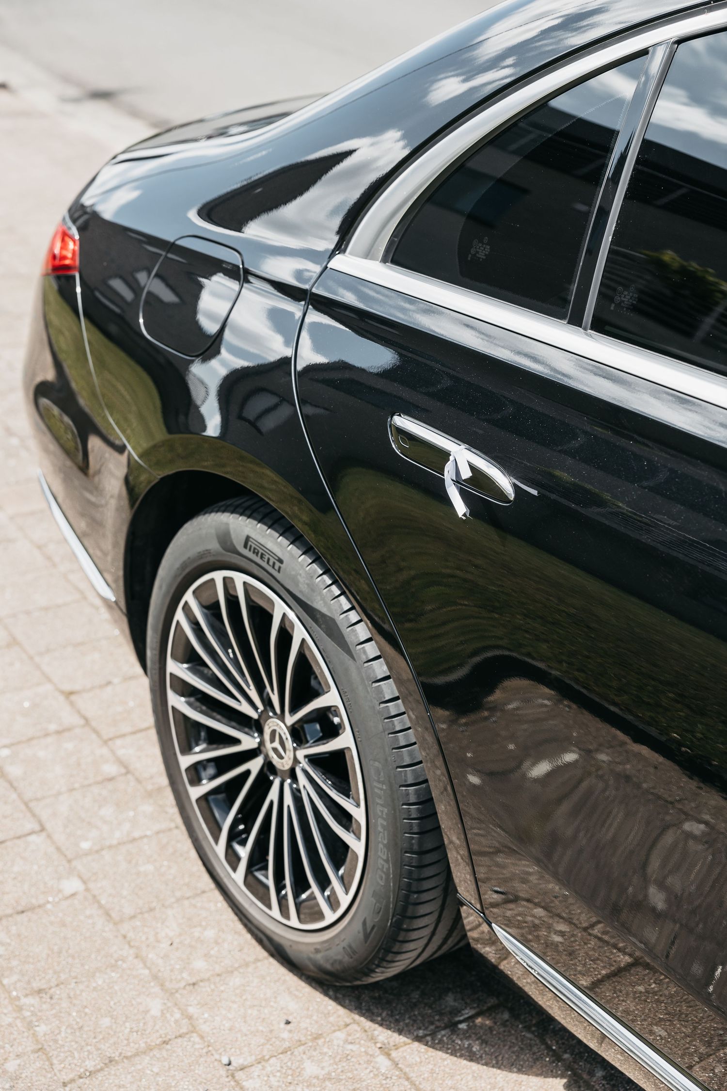 Close-up of a black Mercedes-Benz luxury car showcasing Pirelli tire and elegant multi-spoke alloy wheel on cobblestone.