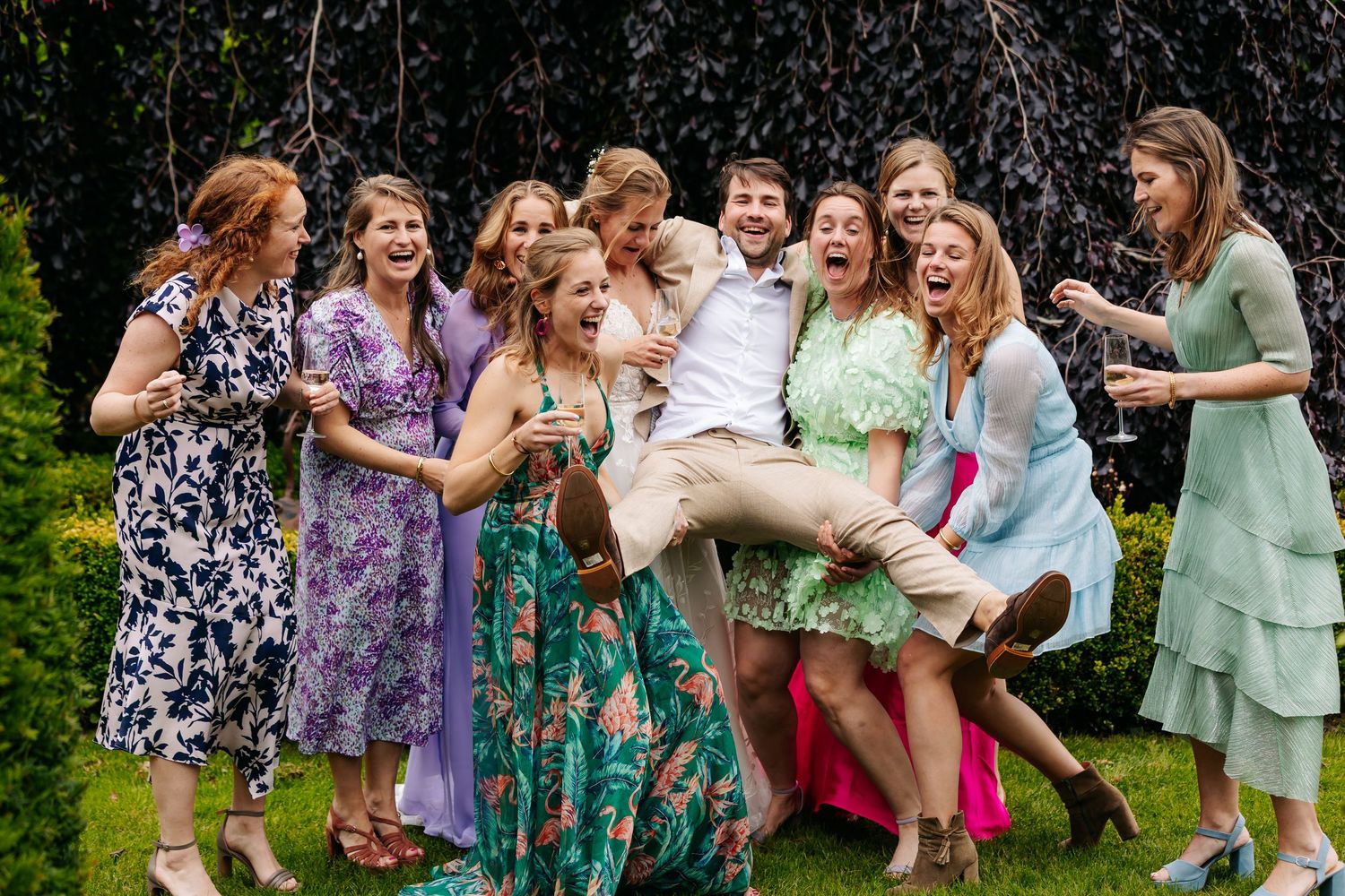 Joyful wedding guests laughing and celebrating together outdoors at lively garden wedding reception.