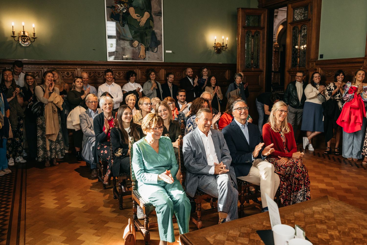 Guests seated and standing in an elegant room during a wedding ceremony.