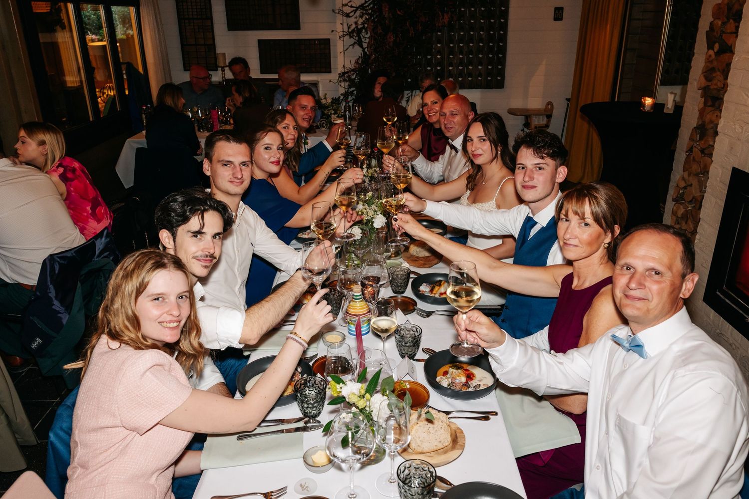Wedding guests raising glasses in a celebratory toast at a decorated reception dinner table.