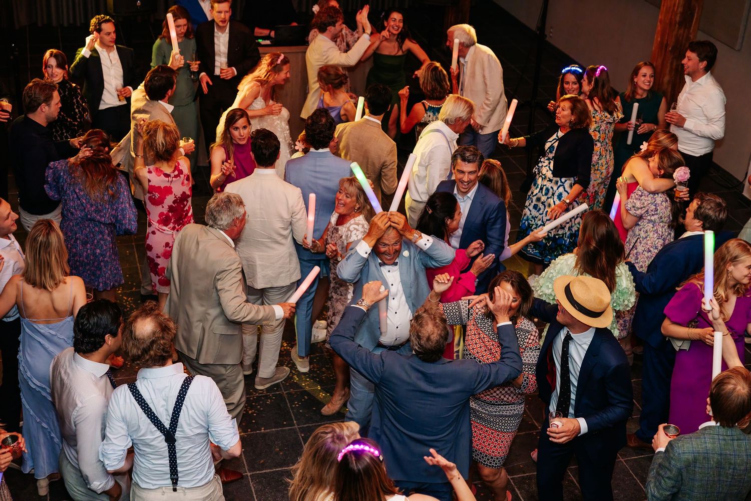 Energetic wedding reception dance floor filled with guests celebrating at night.