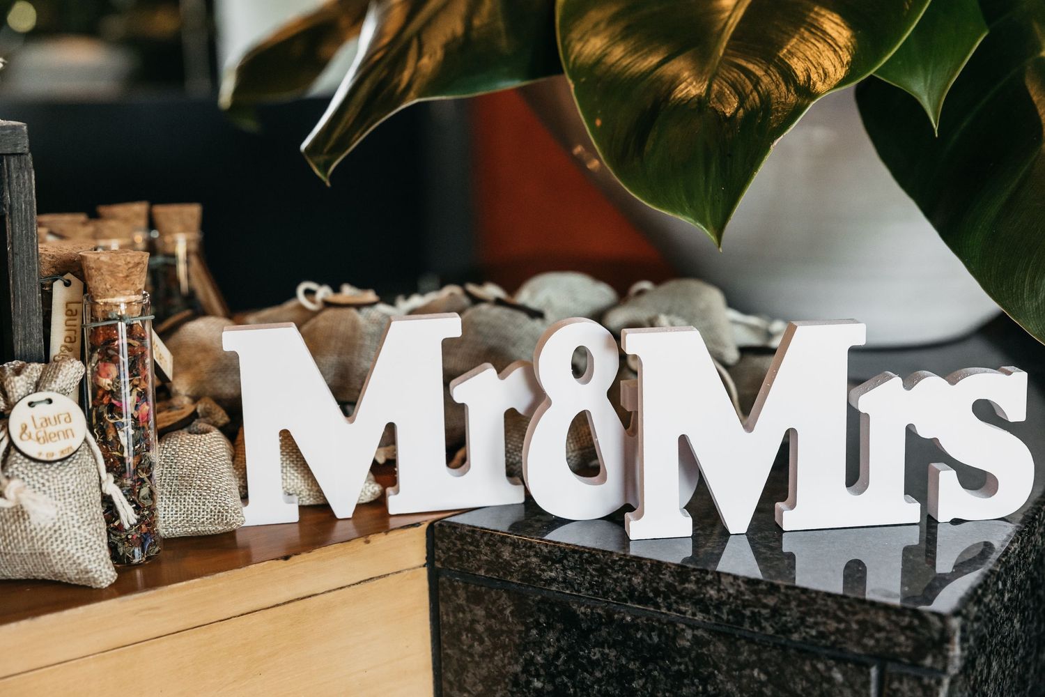 White Mr & Mrs wooden sign displayed on a dark granite surface at a wedding reception.