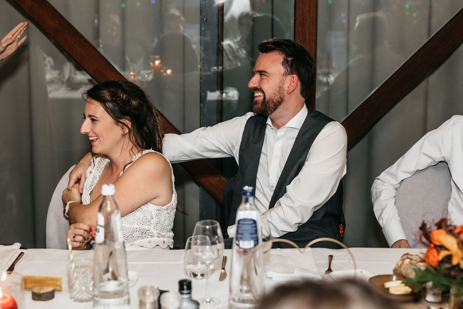 Bride and groom laughing together at the head table during their wedding reception.