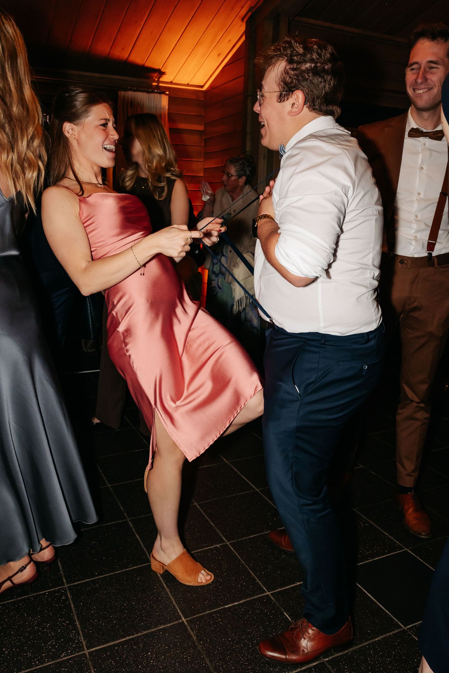 Guests in formal attire dance energetically at a wedding reception party.