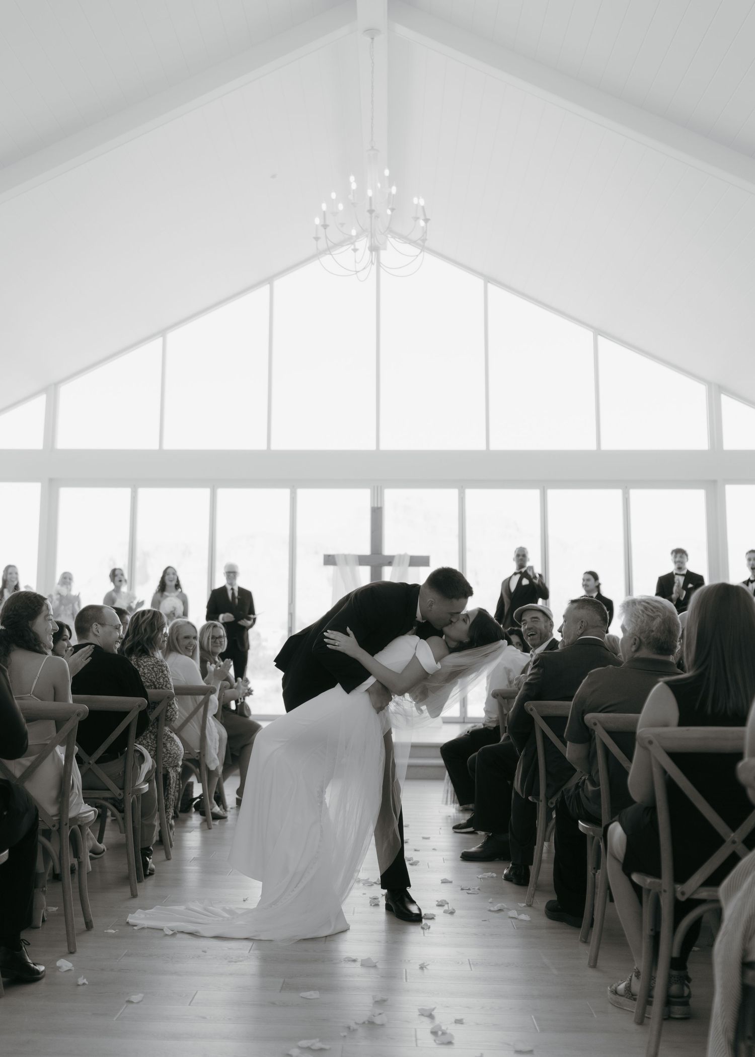 Groom dips bride for a kiss at the altar during an elegant indoor wedding ceremony in a bright chapel.