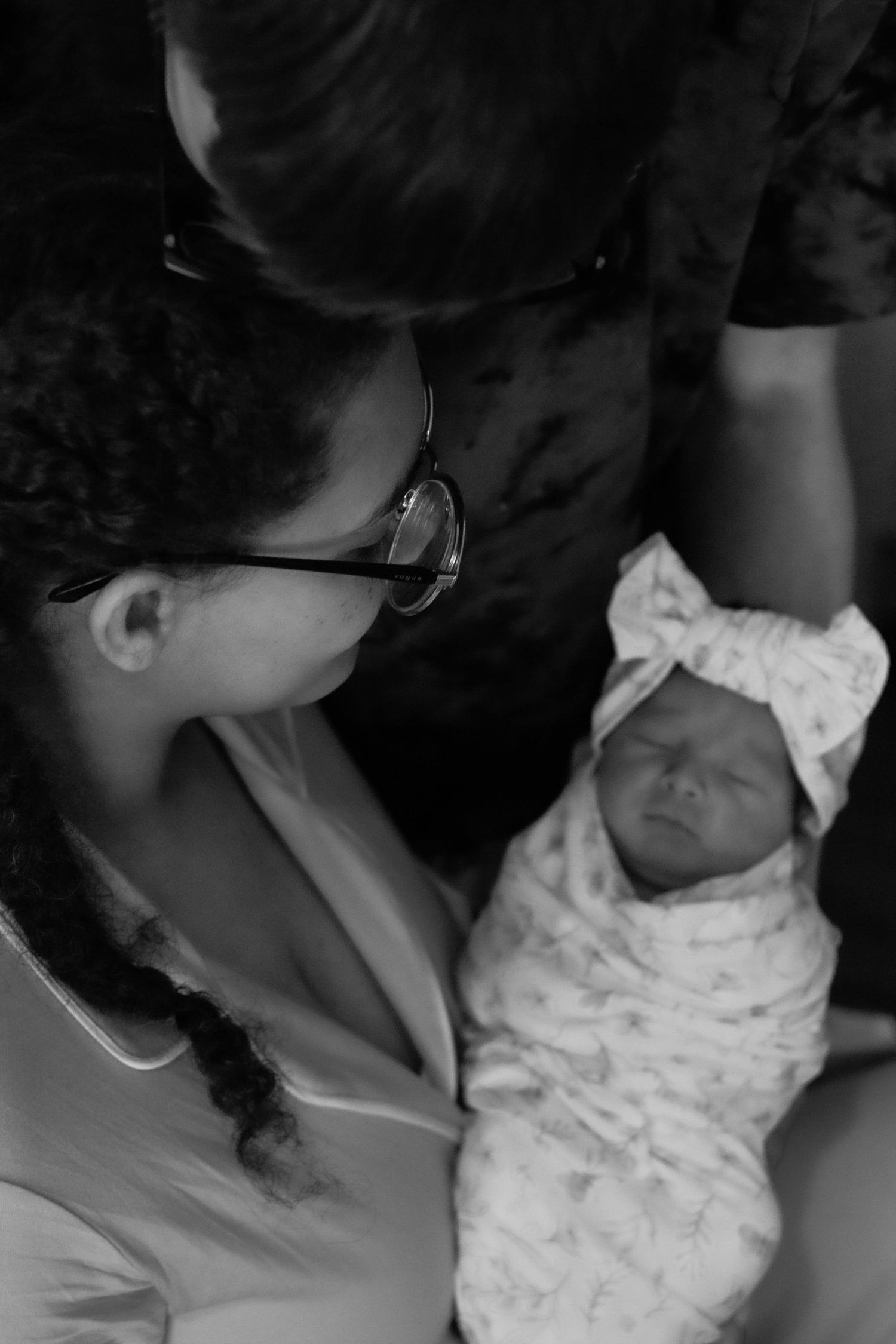 Black-and-white candid of parents admiring their newborn baby.