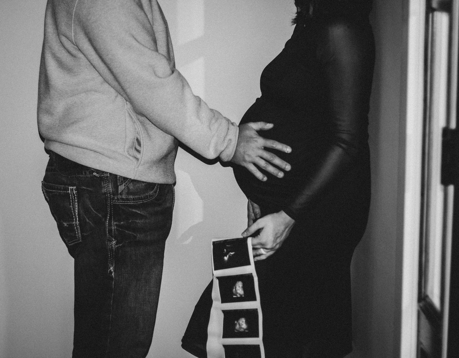 Black-and-white pregnancy announcement showing parents holding ultrasound photos.