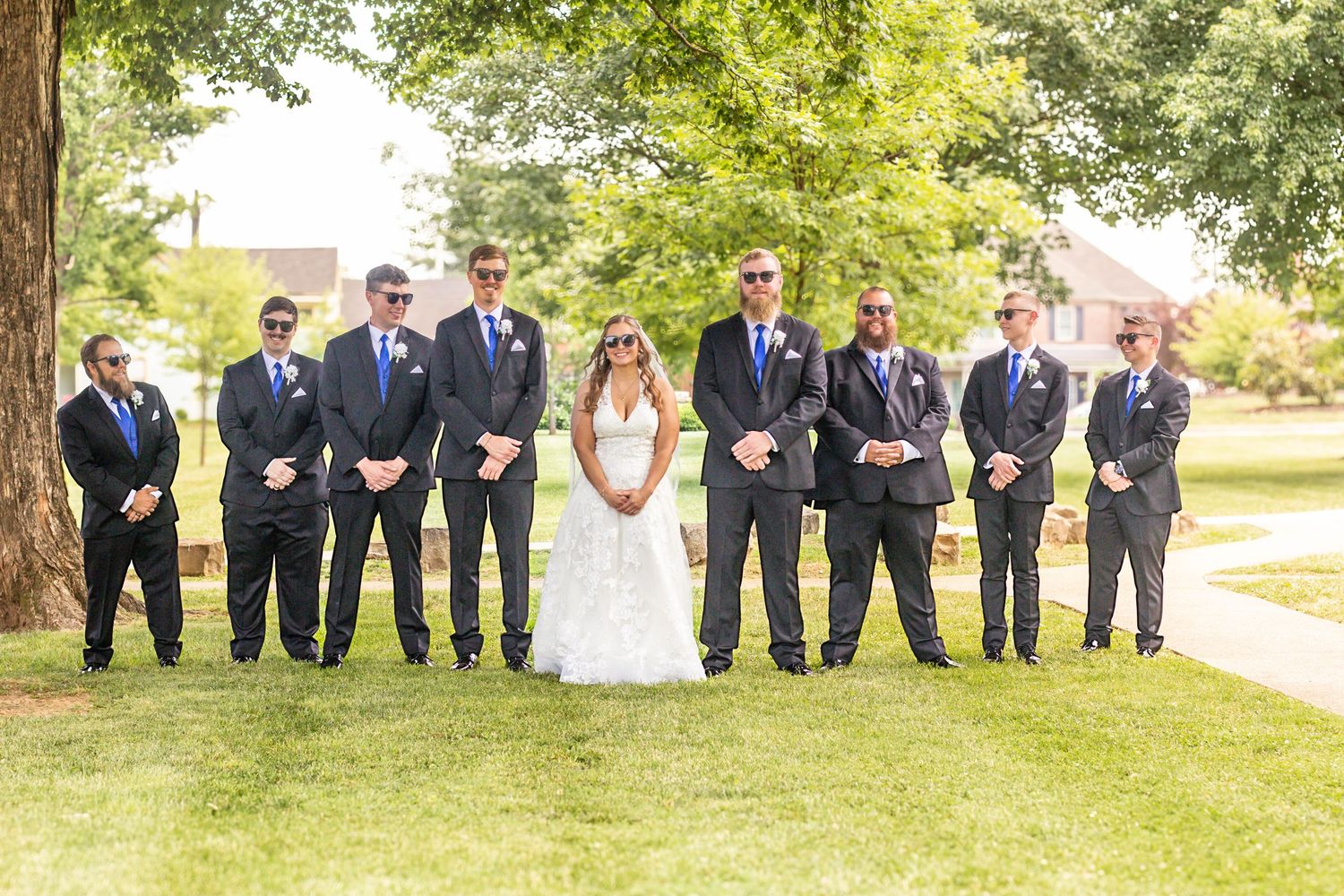 Wedding party posing together outdoors on the lawn.