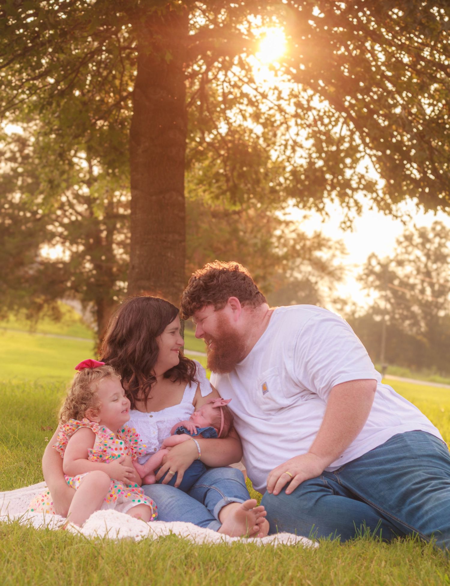 amily cuddling together on a blanket in a sunlit field