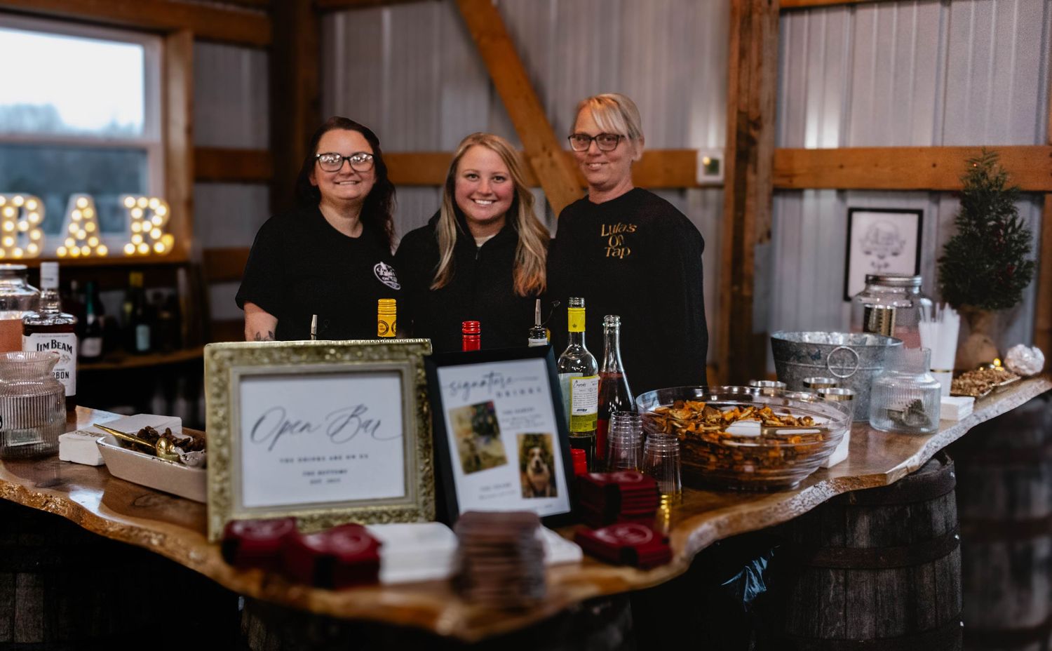 Bartenders behind a fully styled bar setup at a wedding reception.