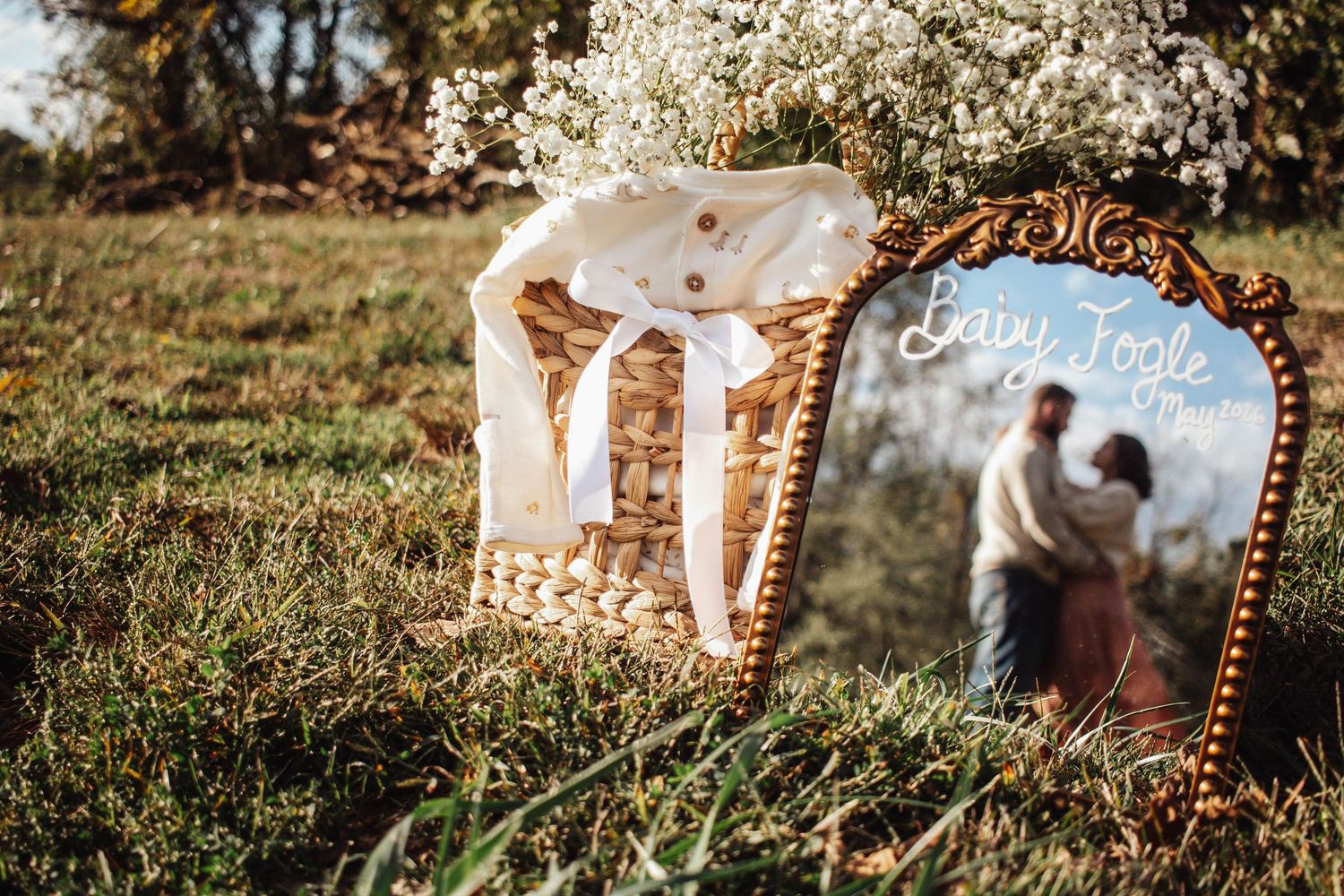 Pregnancy announcement display with baby clothes and ultrasound photos outdoors.