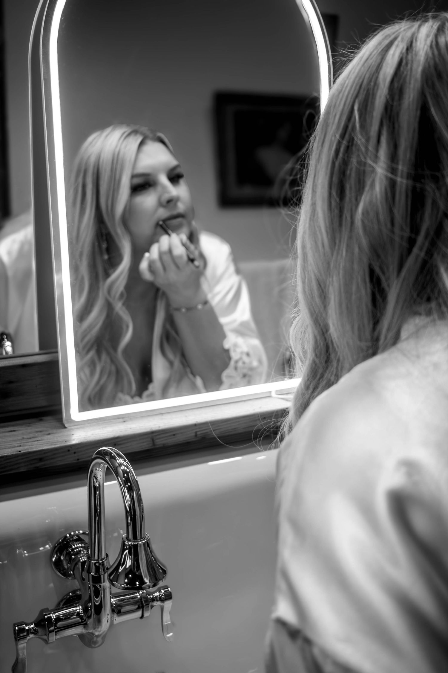 Black-and-white reflection of a bride getting ready in a mirror.