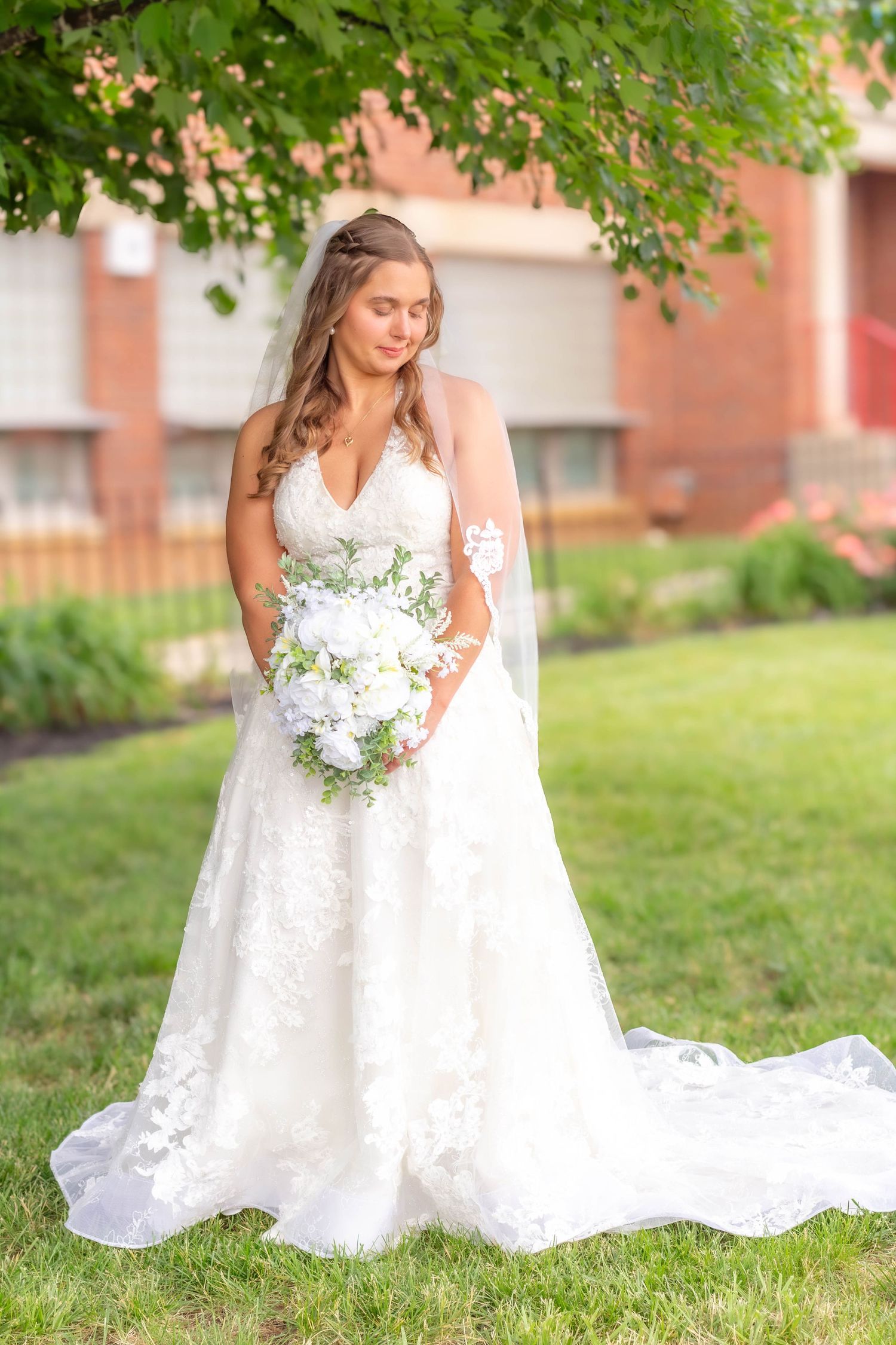 Full-length bridal portrait outdoors with the bride holding her bouquet.