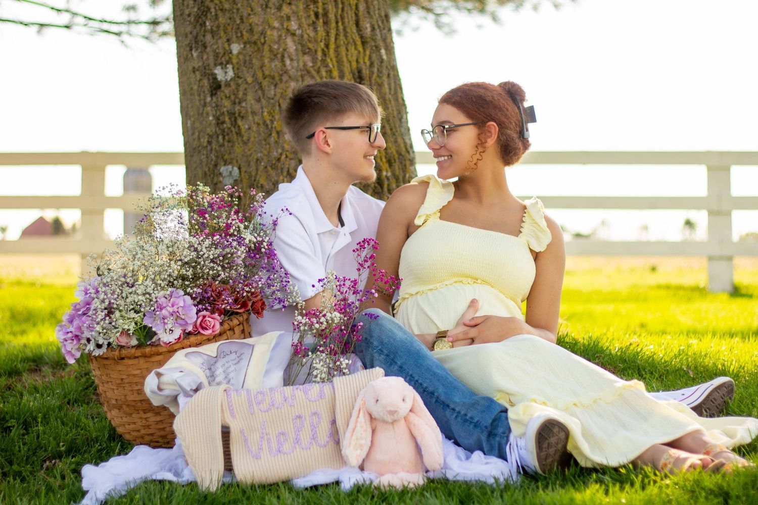 Expecting couple sitting together on a blanket during an outdoor maternity session.
