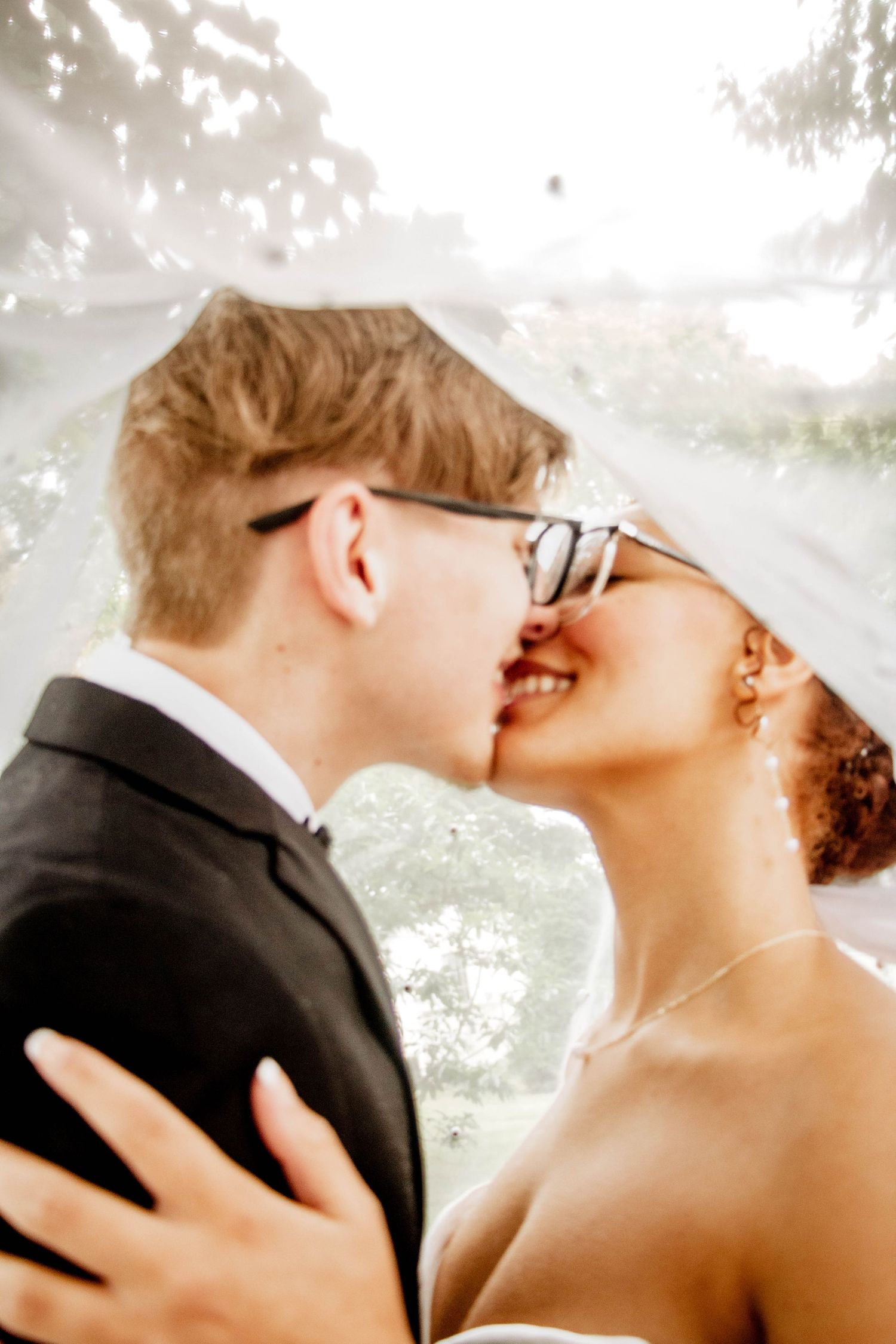Close-up of a bride and groom kissing beneath the wedding veil.