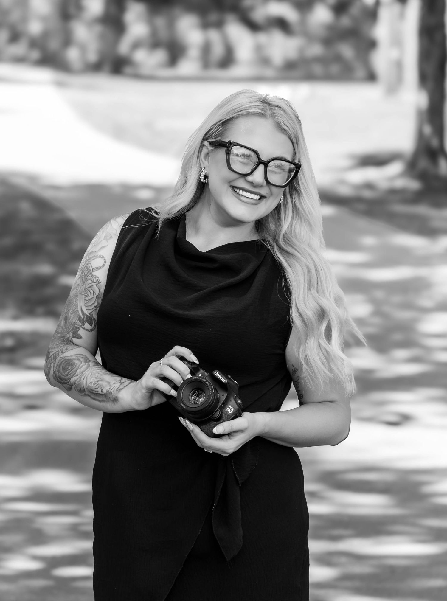 Photographer holding her camera and smiling during an outdoor branding portrait