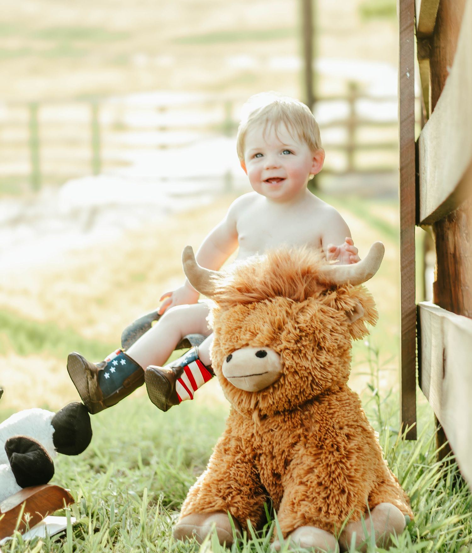 Baby sitting with a stuffed horse during an outdoor milestone session.
