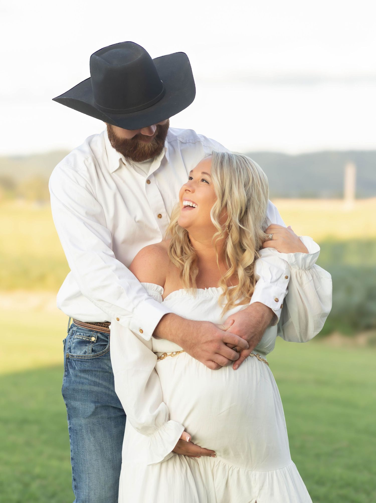 couple looking at each other smiling holding the baby bump