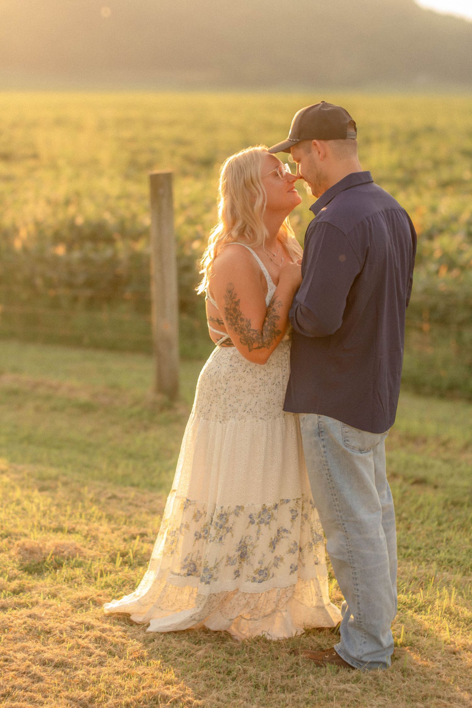 Couple embracing in a field during golden hour.