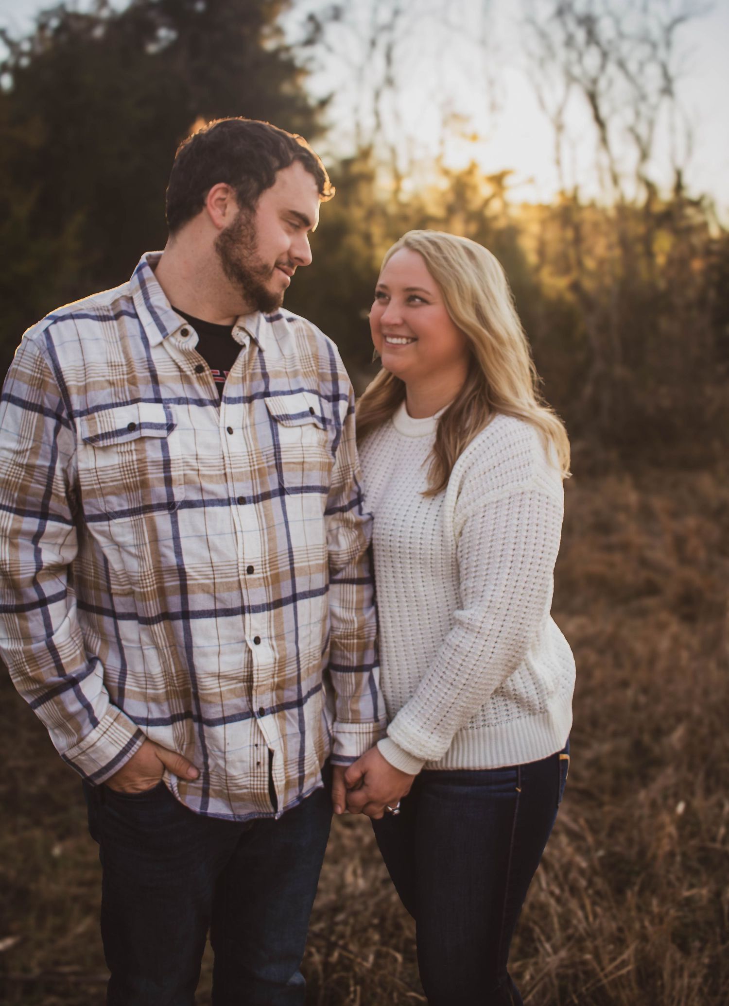Couple holding hands and smiling at each other during an outdoor portrait session