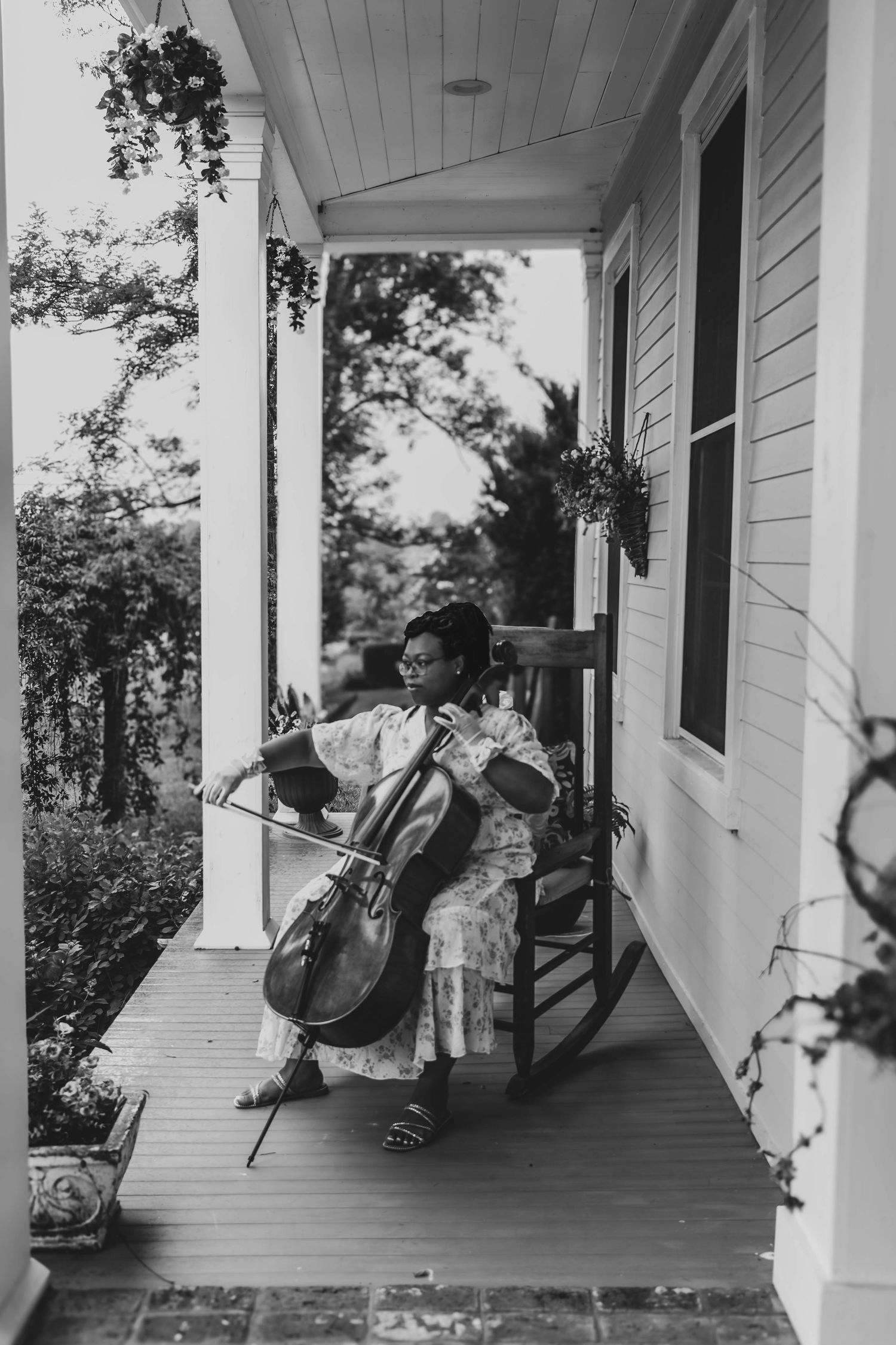 Black-and-white candid of a musician performing on a porch.